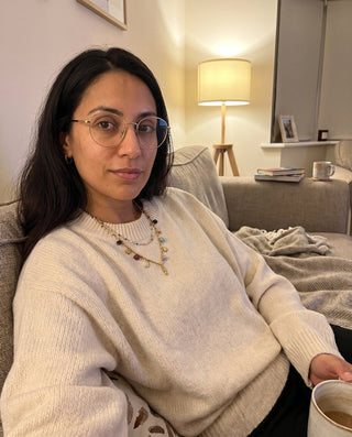 Collana Riva indossata sopra un maglione chiaro sul divano, foto di una cliente