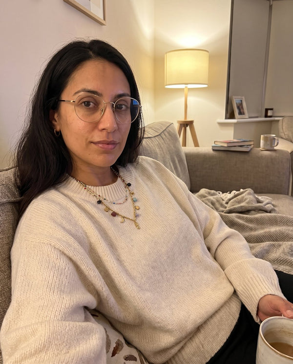Collana Riva indossata sopra un maglione chiaro sul divano, foto di una cliente