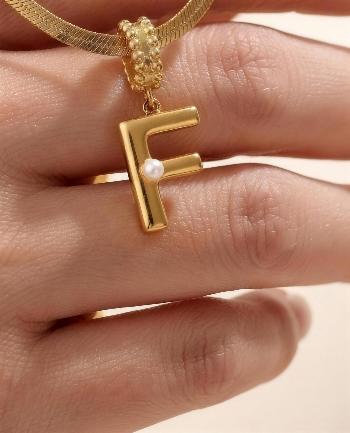 Collana Alma con lettera F in acciaio 316L PVD oro, perlina nella curva