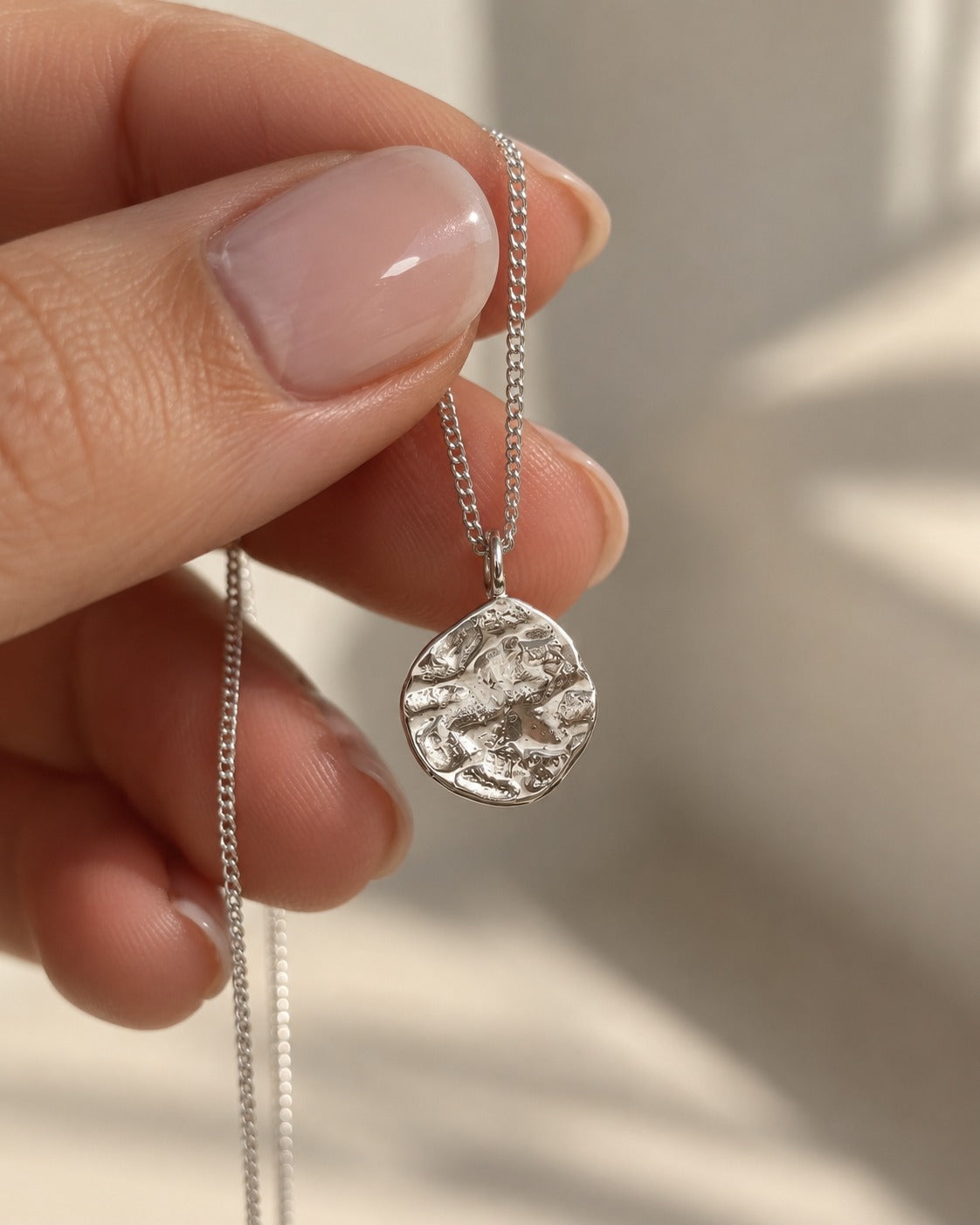 Collana Duna: pendente martellato in argento 925 tenuto tra le dita