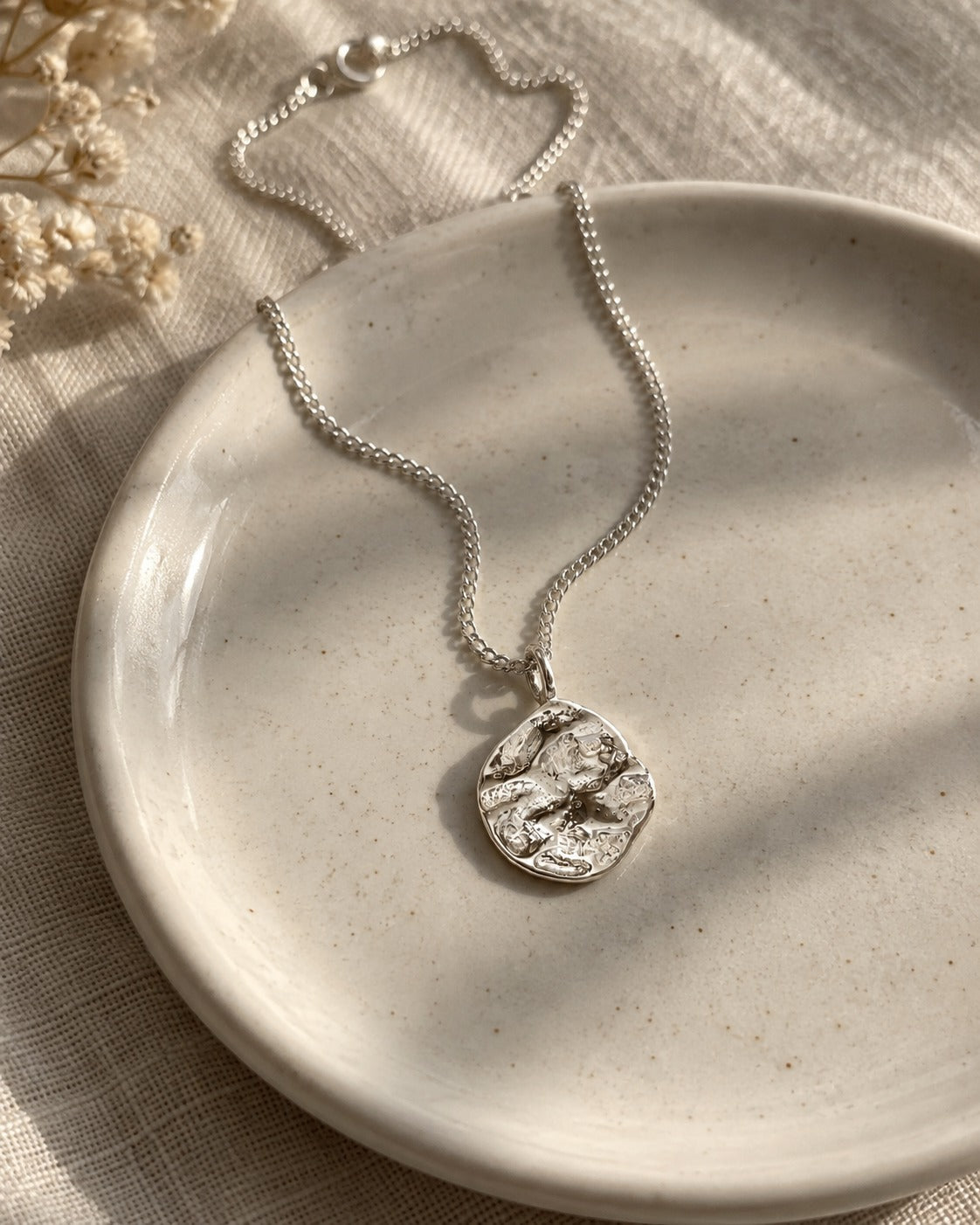 Collana Duna in argento 925 appoggiata su una ciotolina di ceramica