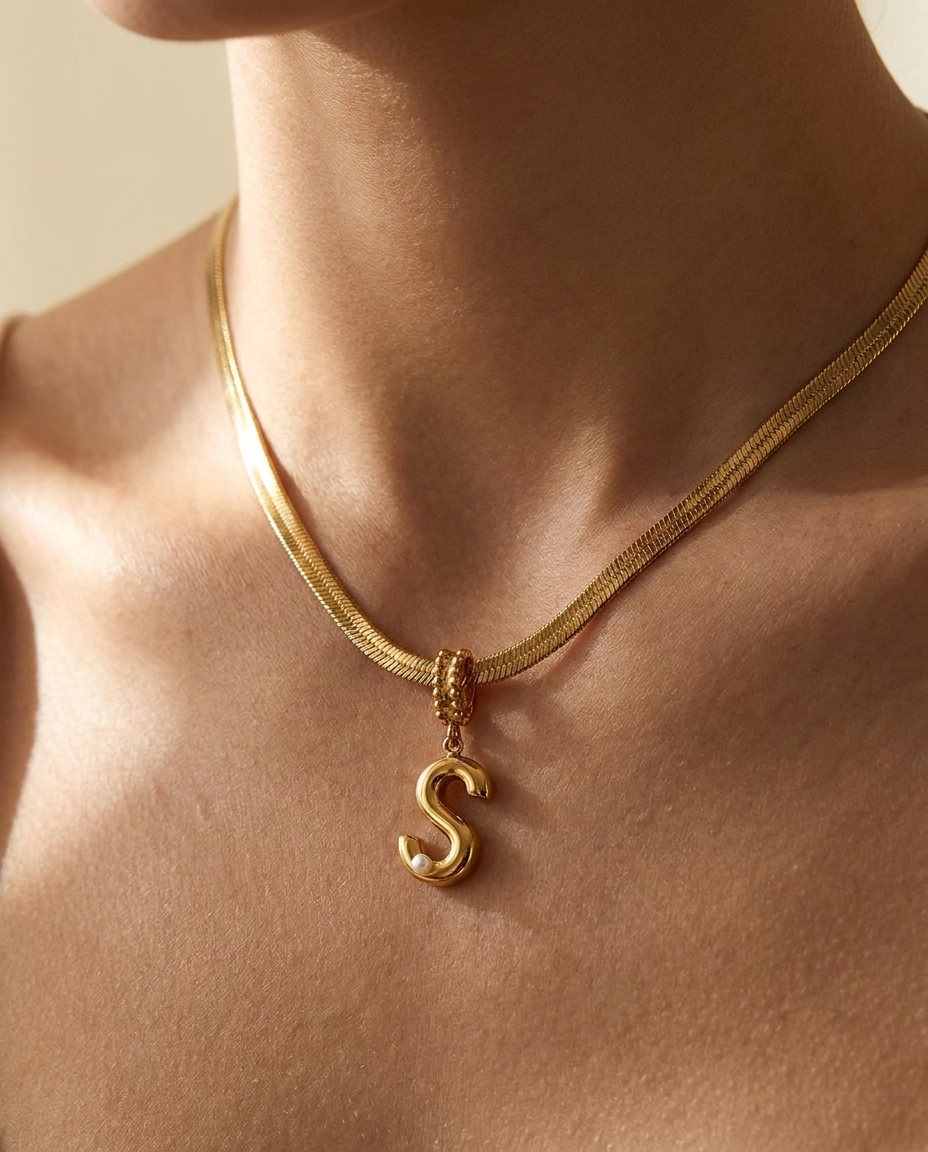 Collana Alma indossata: lettera bombata con perla su catena herringbone piatta
