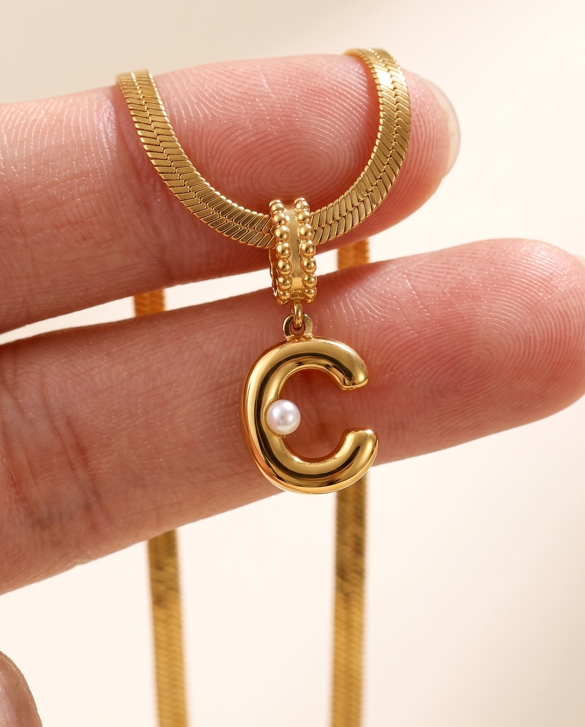 Collana Alma con lettera C in acciaio 316L PVD oro, perlina nella curva