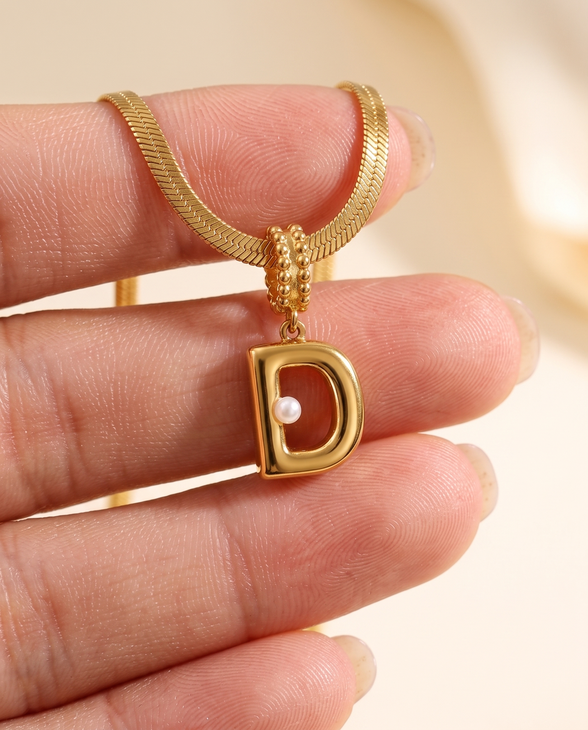 Collana Alma con lettera D in acciaio 316L PVD oro, perlina nella curva
