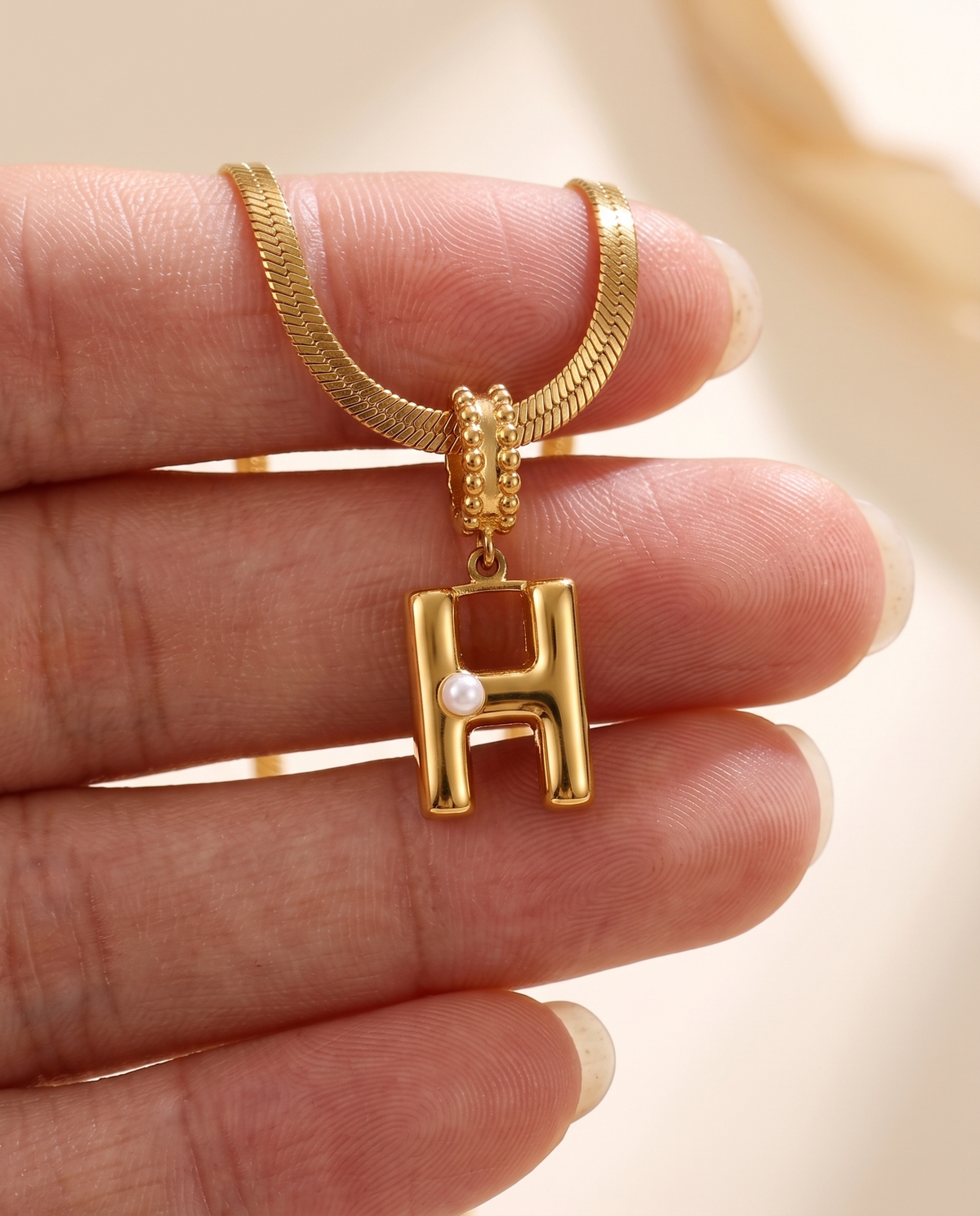 Collana Alma con lettera H in acciaio 316L PVD oro, perlina nella curva