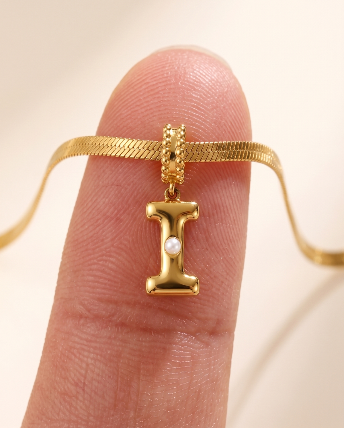 Collana Alma con lettera I in acciaio 316L PVD oro, perlina nella curva