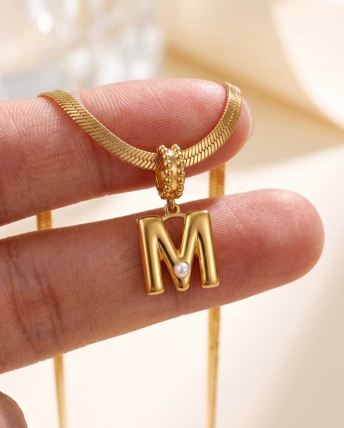 Collana Alma con lettera M in acciaio 316L PVD oro, perlina nella curva
