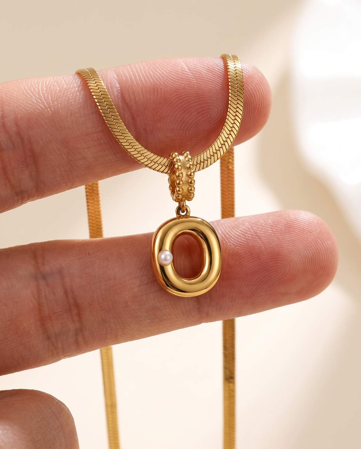 Collana Alma con lettera O in acciaio 316L PVD oro, perlina nella curva