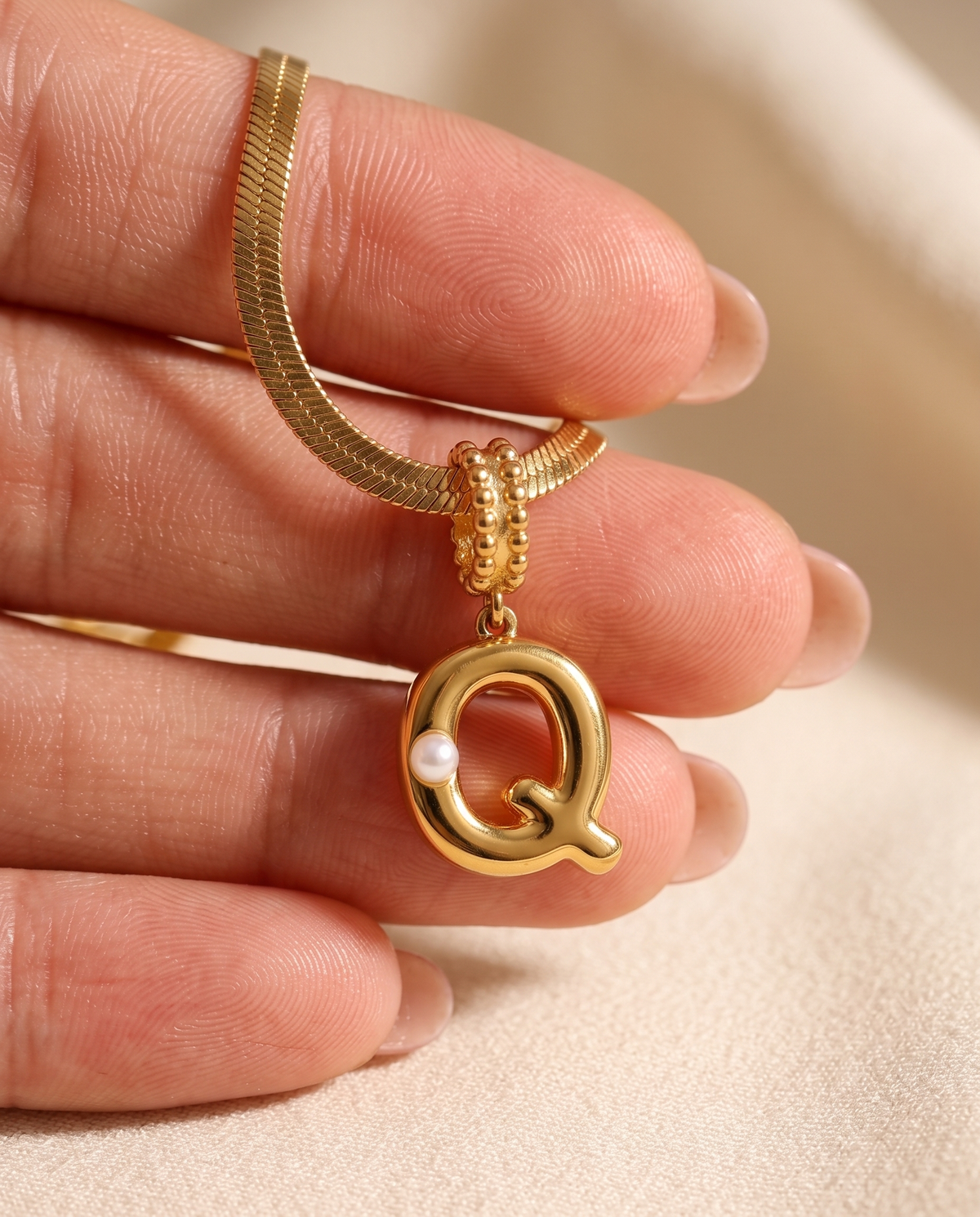 Collana Alma con lettera Q in acciaio 316L PVD oro, perlina nella curva