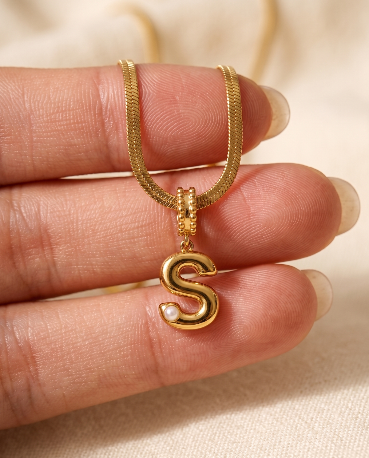 Collana Alma con lettera S in acciaio 316L PVD oro, perlina nella curva